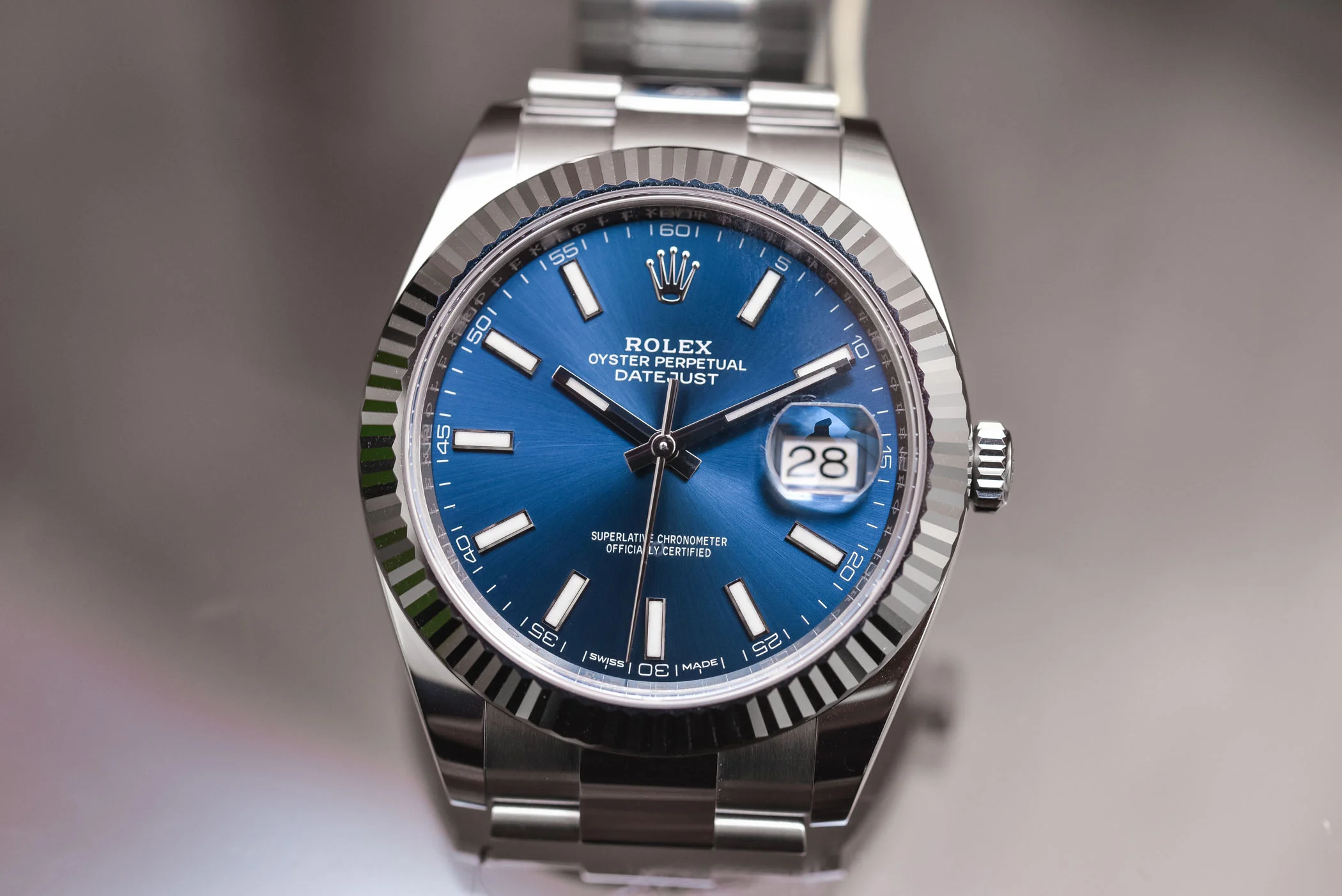 Close-up of a genuine Rolex Datejust 41 with bright blue sunray dial, fluted white-gold bezel, and polished Jubilee links, highlighting the Cyclops date magnification and applied indexes.